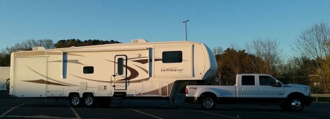a large white truck pulls a long fifth wheel camper