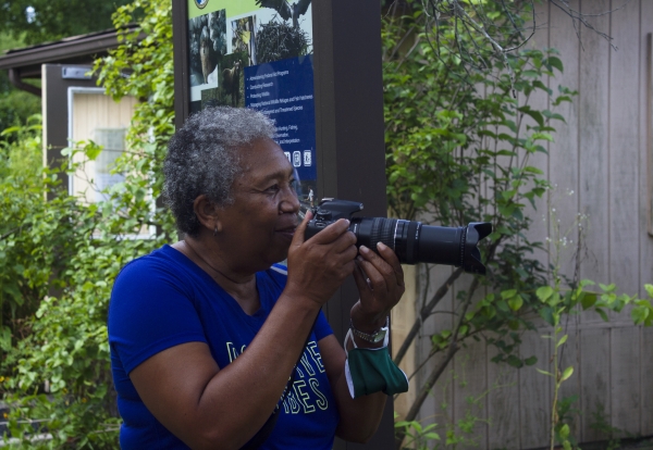 Elderly lady holding DSLR camera and preparing to take a picture.