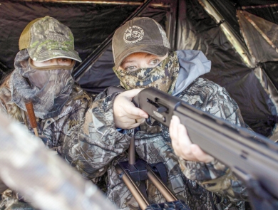 Two hunters in camouflage waiting in a hunting blind