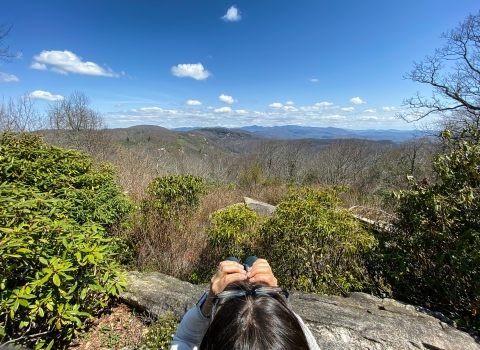 Person holding binoculars looking into the distance