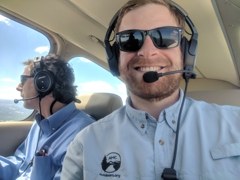 Photo shows two men sit in what appears to be a small aircraft 