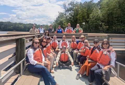Staff and leadership from the Rappahannock Tribe,	the	U.S. Fish and Wildlife Service,	the	Virginia Department of Historic Resources and The Conservation Fund gather on the dock and boat. 