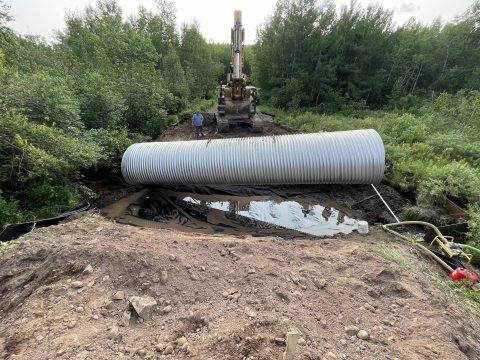 Placing the cyclone pipe into the Wilson Creek after the site was excavated for the culvert installation