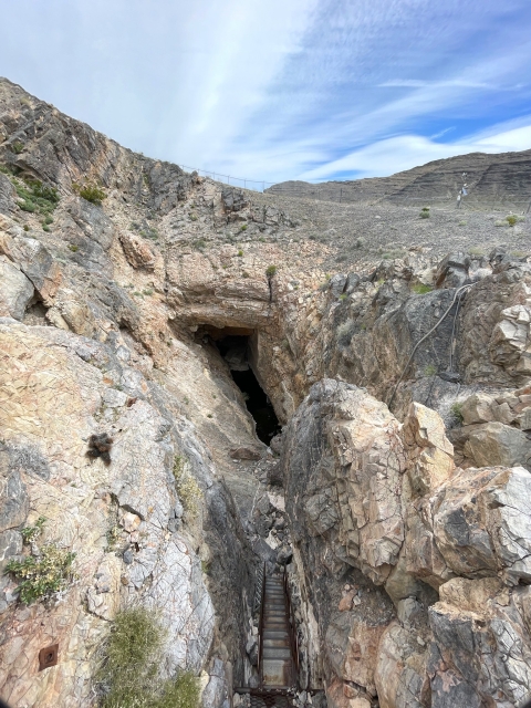 A cave entrance on the side of a limestone cliff