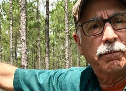 Salem Saloom leans against a longleaf pine tree.