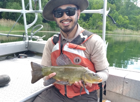 Image of biologist holding a fish in a boat.