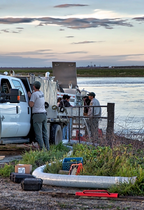 A truck, people and equipment by a river