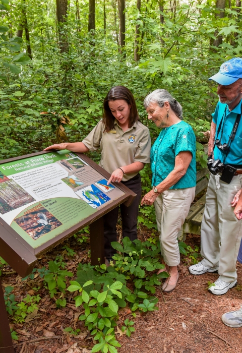 FWS Visitor services staffer shows interpretive panel to visitors