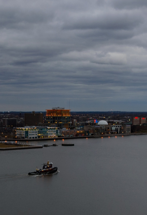an aerial view of a city and a river at dusk with cloudy skies