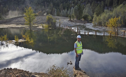 a man standing on a log next to a body of water
