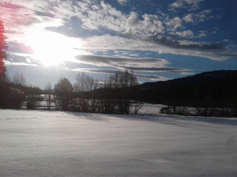 Snow covered hills at Little Pend Oreille National Wildlife Refuge, with sun streaming through scattered clouds. 