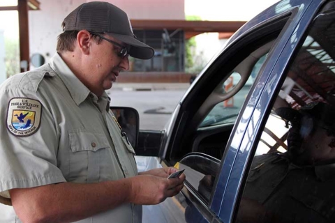 Wildlife Inspector Jeff Moore stands in next to an open car window to speak to the driver.