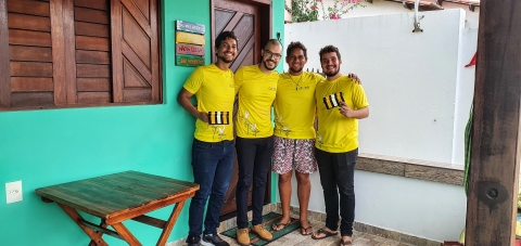 Four people in yellow t-shirts are holding power line markers