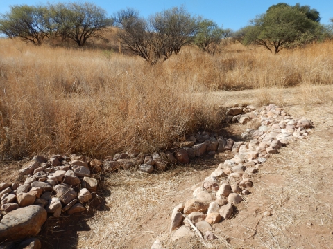 A structure built out of rocks in a grassland