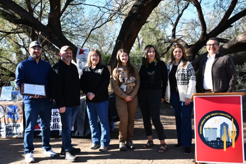 seven people stand together smiling in front of a podium that says Tucson urban bird treaty coaltion