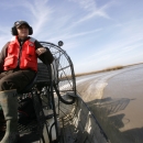 Biologist navigating through a coastal marsh habitat via airboat.