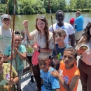 Youth pose with a fish and U.S. Fish and Wildlife Service staff at the 2024 Cops and Bobbers Fishing Program 