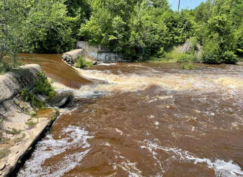 a breached dam with river water flowing through the gap