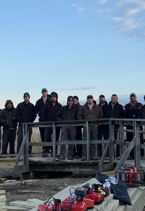 a group of people stand on a boardwalk during a construction project