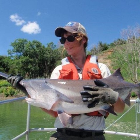 Maegan Spindler in her Service uniform holding a paddlefish in a boat. Image from In Memory of Robert Allan Klumb Facebook page, https://www.facebook.com/RobertAllanKlumb/photos/a.527813793939504/545656032155280/.
