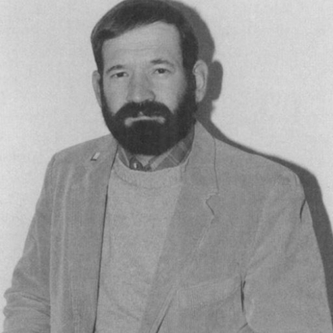 A black and white headshot of a person smiling.