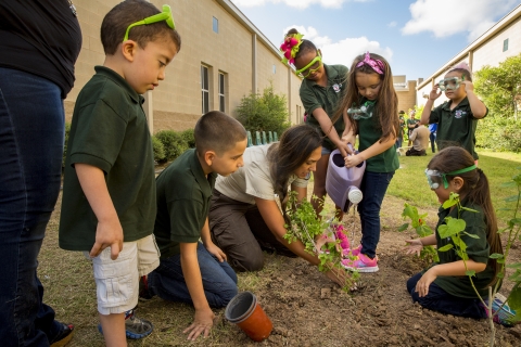 Young children help a refuge leader plant a pollinator garden at their elementary school in Texas.