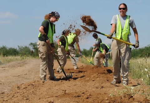 Five volunteers with shovels are building a trail