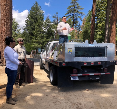 A man delivering a speech while standing on the back of a Service truck