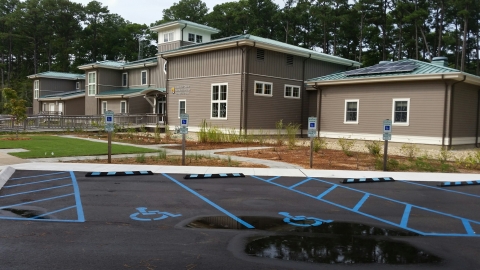 A brown-and-white building with a garden and several parking spaces