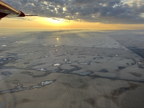 view of an airplane wing over a landscape of wetlands