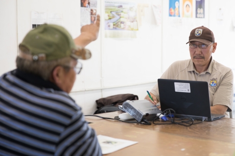 A government employee writes notes while listening to an indigenous elder