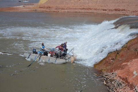 Image of 3 researchers on a raft by a waterfall