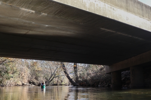 Woman in a river beneath a road bridge