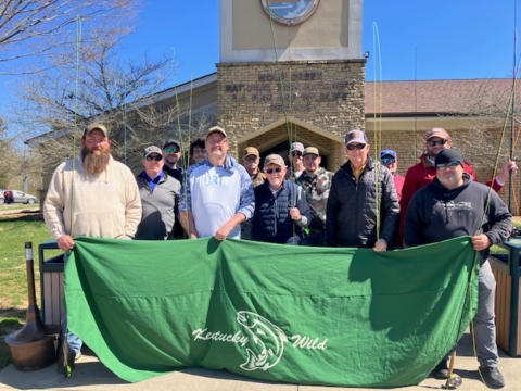 Group of anglers holding rods and a banner for group photo