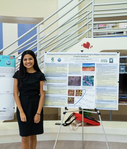 Nikki Imamura stands in front of a poster board exhibit