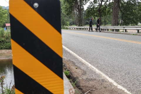 Two biologists wearing wetsuits crossing a bridge