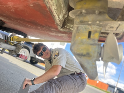 USFWS watercraft inspector views underside of boat for invasive species.
