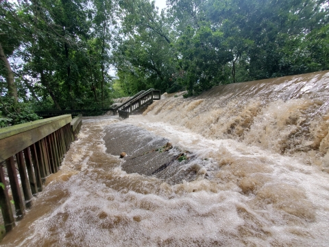 Flood waters overtopping the dike and flowing down the boardwalk stairs and ramp.