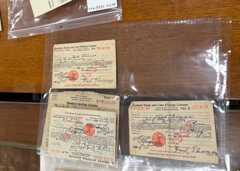 Collection of old paper fishing licenses from the 1930s in protective bender at NCTC.