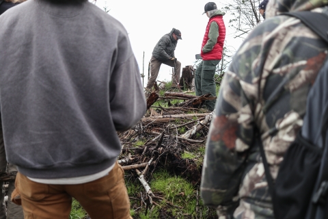 Man plants a small tree while several others look on
