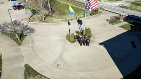 people at base of flagpoles with US flag at top and3 others below