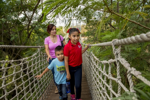 A woman and two children cross a rope bridge at Santa Ana National Wildlife Refuge in Texas.