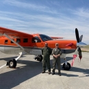 two people standing in front of an airplane