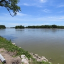 A broad, calm, river, with trees on the far bank and blue skies above.