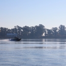 A boat is pictured in the middle of a tree lined river