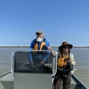 Two Service biologists stand in a boat near the coast of Texas.
