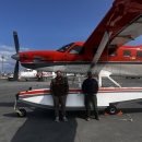 two pilot biologist standing by a plane