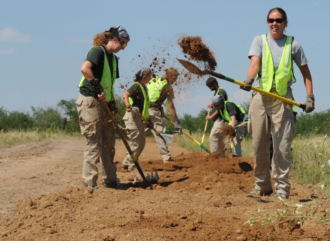 Five volunteers with shovels are building a trail
