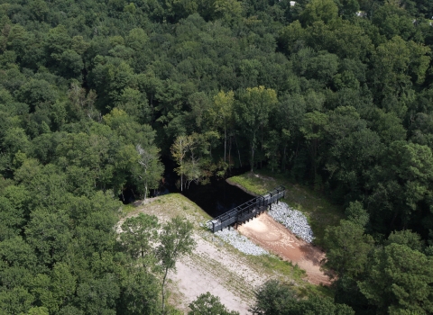 A metal structure dams a ditch and prevents water from flowing out.